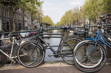 Amsterdam, Hollanda - 20 Nisan 2017: Köprüsü'nde merkezi Amsterdam Hollanda kanal üzerinde park etmiş Bisiklet 