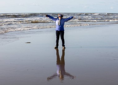 Katwijk; Hollanda - 23 Nisan; 2017: bir kadın sahilde etkindir ve ıslak kum üzerinde bir ayna görüntüsü vardır. Katwijk. Hollanda