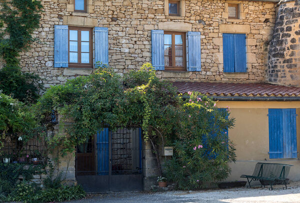 Facade of an old stone house with wooden shutters in Carlux. Dordogne valley, Aquitaine, France