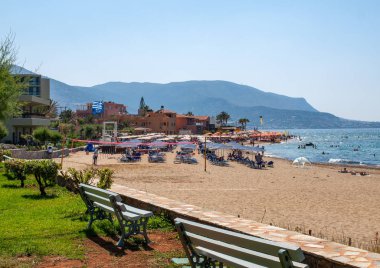 Malia, Girit, Yunanistan-Juni 18, 2019: Insanlar Malia, Girit, Yunanistan plajda güneşli bir günde dinleniyor