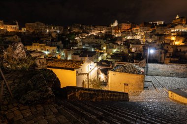 Matera 'daki antik Sassi bölgesinde geceleri, antik mağara evleri ile tanınan şaşırtıcı aydınlık binalar. Basilicata. İtalya
