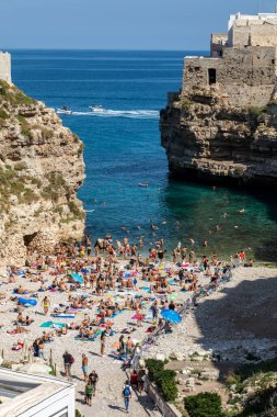 Polignano, İtalya - 17 Eylül 2019: İnsanlar Polignano a Mare, Adriyatik Denizi, Apulia, Bari ili, İtalya 'daki sevimli Lama Monachile plajında dinleniyor ve yüzüyorlar,