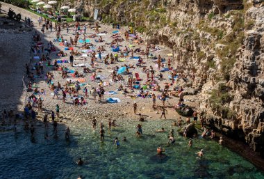 Polignano a Mare, İtalya - 17 Eylül 2019: İnsanlar Polignano a Mare, Adriyatik Denizi, Apulia, Bari ili, İtalya 'daki sevimli Lama Monachile plajında dinleniyor ve yüzüyorlar,