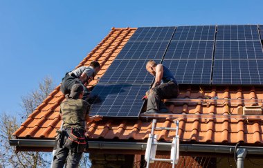 Ochojno, Polonya - 8 Nisan 2020: İşçiler Ochojno 'da bir evin çatısına güneş enerjisi panelleri kuruyorlar. Polonya