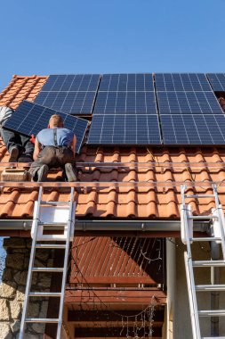 Ochojno, Polonya - 8 Nisan 2020: İşçiler Ochojno 'da bir evin çatısına güneş enerjisi panelleri kuruyorlar. Polonya