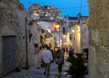 Matera, İtalya - 15 Eylül 2019: Matera şehrinin tarihi bir bölgesi olan Sassi di Matera 'daki Cobblestone caddesinde yürüyüş yapan turistler. Basilicata. İtalya