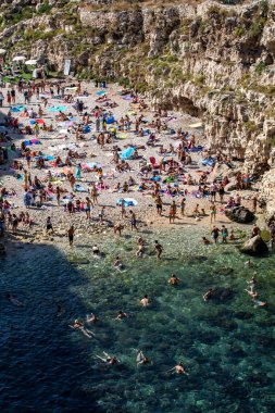 Polignano a Mare, İtalya - 17 Eylül 2019: İnsanlar Polignano a Mare, Adriyatik Denizi, Apulia, Bari ili, İtalya 'daki sevimli Lama Monachile plajında dinleniyor ve yüzüyorlar,