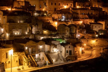 Matera 'daki antik Sassi bölgesinde geceleri, antik mağara evleri ile tanınan şaşırtıcı aydınlık binalar. Basilicata. İtalya