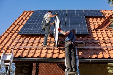 Ochojno, Polonya - 8 Nisan 2020: İşçiler Ochojno 'da bir evin çatısına güneş enerjisi panelleri kuruyorlar. Polonya