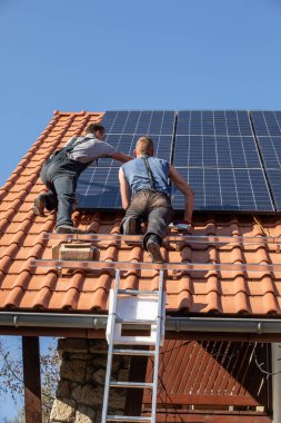  İşçiler Ochojno 'da bir evin çatısına güneş enerjisi panelleri kuruyorlar. Polonya