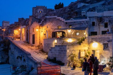 Matera, İtalya - 18 Eylül 2019: Matera, İtalya 'nın akşam manzarası, Sassi di Matera şehrinin tarihi bir bölgesi olan Sassi di Matera' daki kaldırım kafelerinin avlularını aydınlatan renkli ışıklarla. Basilicata. İtalya