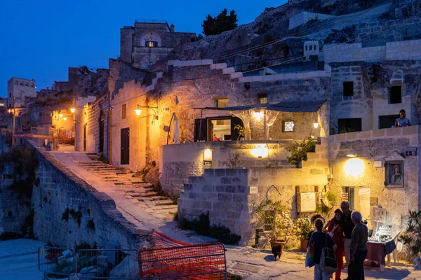 Matera, İtalya - 18 Eylül 2019: Matera, İtalya 'nın akşam manzarası, Sassi di Matera şehrinin tarihi bir bölgesi olan Sassi di Matera' daki kaldırım kafelerinin avlularını aydınlatan renkli ışıklarla. Basilicata. İtalya