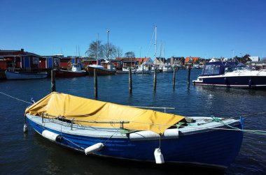 Raa, İsveç - 21 Nisan 2018: marinada mavi gökyüzü altında hiç insan olmadan duran sarı branda kaplı tekne. Raa - Güney İsveç 'te Helsingborg' un güneyinde bulunan eski bir balıkçı köyü.