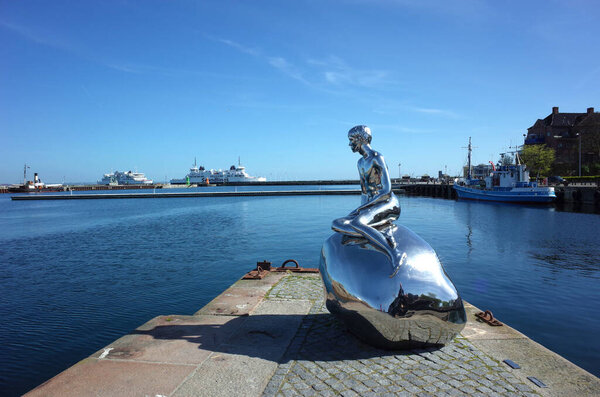 Helsingor, Denmark - 06 May, 2018: Sculpture "Han" of naked young man siting on stone gazing at sea by Michael Elmgrin and Ingar Dragset, Sculpture repeats pose of Mermaid in Copenhagen