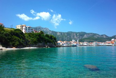 Kokkari, Samos Adası, Yunanistan - 15 Mayıs 2018: Kokkari balıkçı köyünün kıyı manzarası taş tabanı kristal temiz su altında ve zemin üzerinde dağ