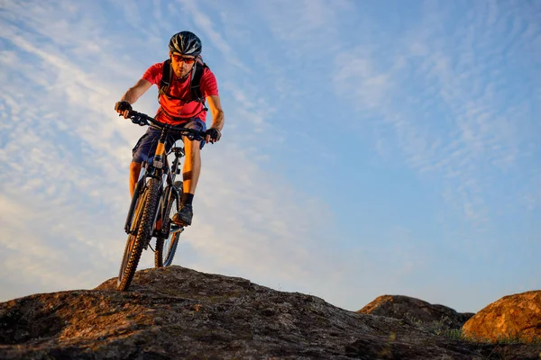 Radfahrer in Rot fährt mit dem Fahrrad den Felsen vor blauem Himmel hinunter. Extremsport und Enduro-Konzept. — Stockfoto