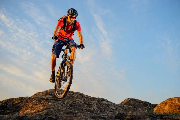Ποδηλάτης στο κόκκινο ιππασίας το ποδήλατο κάτω από το βράχο στο φόντο μπλε του ουρανού. Extreme Sport και έννοια ποδήλατο Enduro. — Φωτογραφία Αρχείου
