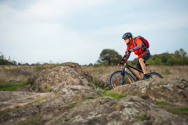 Radler in Rot bei Sonnenuntergang auf dem steinigen Weg. Extremsport und Enduro-Konzept. — Stockfoto