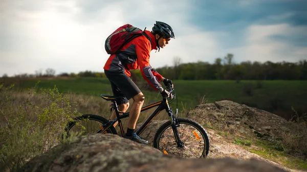 Radler im roten Fahrrad auf dem steinigen Weg am Abend. Extremsport und Enduro-Konzept. — Stockfoto