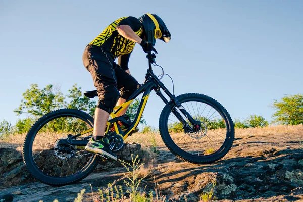 Professional Cyclist Riding the Downhill Mountain Bike on the Summer Rocky Trail at the Evening. Extreme Sport and Enduro Cycling Concept.