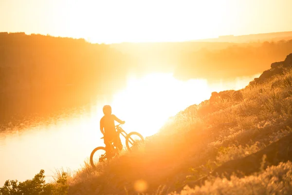 Cyklist plocka sin Mountain Bike upp sommaren Rocky spåret på kvällen. Extrem Sport och Enduro cykling koncept. — Stockfoto