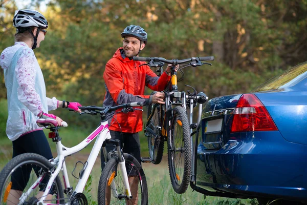 Unga par demontera mountainbikes från cykel Rack på bilen. Äventyr och familj resa koncept. — Stockfoto