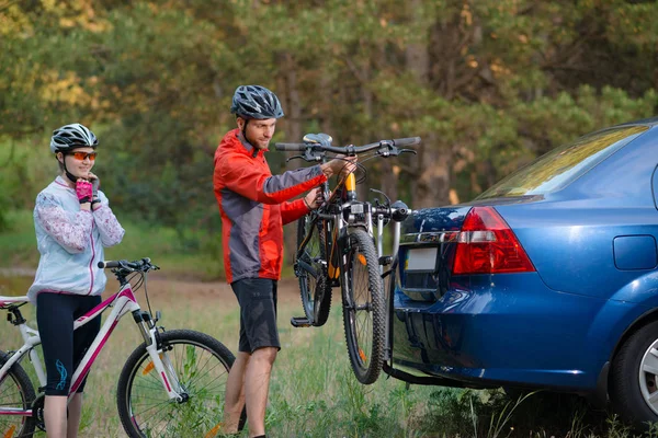 Coppia giovane Smontaggio Mountain Bike da Bike Rack sulla vettura. Concetto avventura e viaggio in famiglia . — Foto Stock