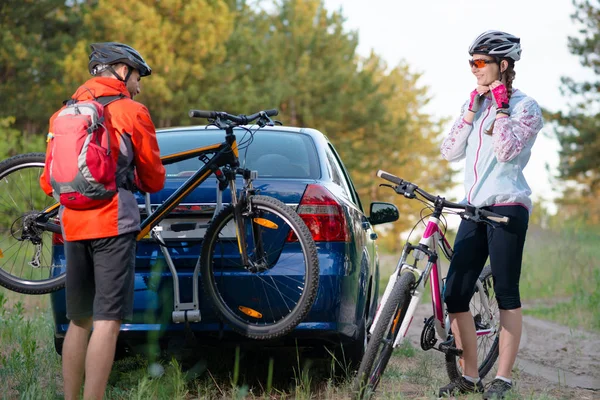 Jeune couple Démontage de vélos de montagne à partir du porte-vélos sur la voiture. Concept Aventure et voyage en famille . — Photo