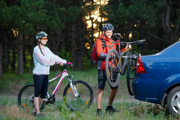 Young Couple Unmounting Mountain Bikes from Bike Rack on the Car. Adventure and Family Travel Concept. — Stock Photo, Image