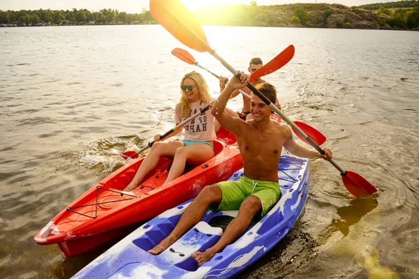 Vänner att ha kul på kajaker på vacker flod eller sjö vid solnedgången — Stockfoto