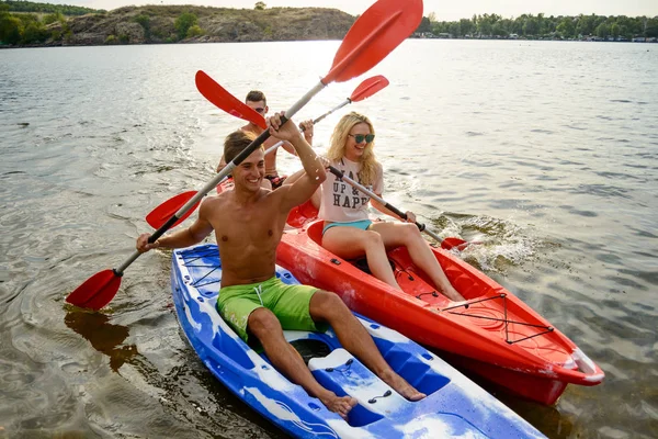 Vänner att ha kul på kajaker på vacker flod eller sjö vid solnedgången — Stockfoto