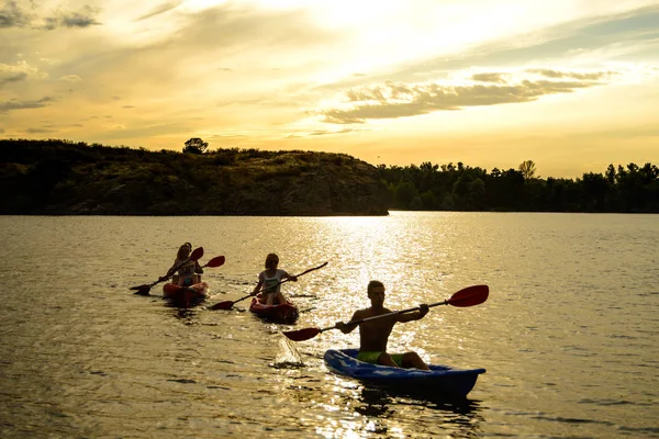 朋友们在日落的夜空下 在美丽的河流或湖泊上划独木舟 — 图库照片