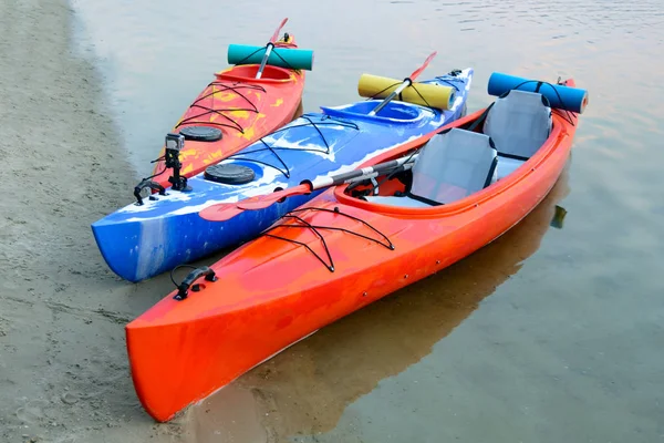 Three Traveling Kayaks on the Sand Beach near Beautiful River or Lake at the Evening. Travel, Adventure and Water Recreation Concept.