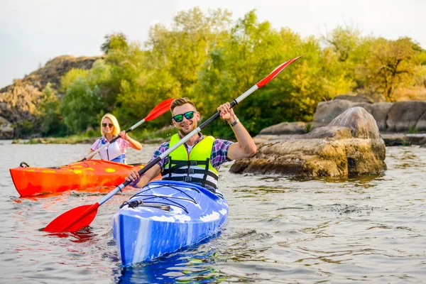 Genç mutlu çift kürek çekmeye Kayaks güzel nehir ya da göl üzerinde — Stok fotoğraf