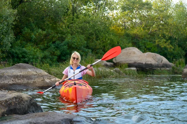 Jeune femme pagayant kayak sur belle rivière ou lac parmi les pierres à la soirée — Photo