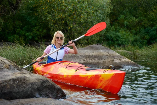 Jeune femme pagayant kayak sur belle rivière ou lac parmi les pierres à la soirée — Photo