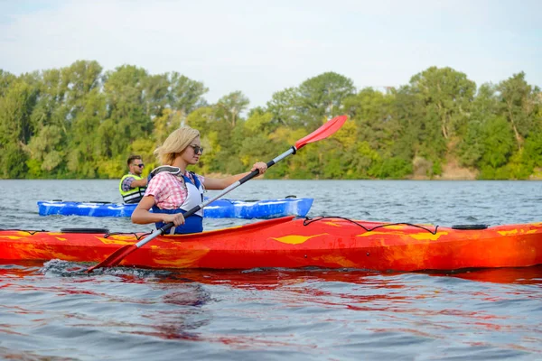 Junges glückliches Paar paddelt Kajaks auf wunderschönem Fluss oder See — Stockfoto