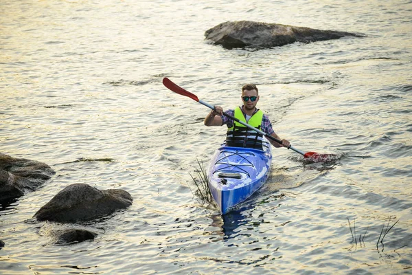 Homme pagayant kayak sur belle rivière ou lac parmi les pierres à la soirée — Photo