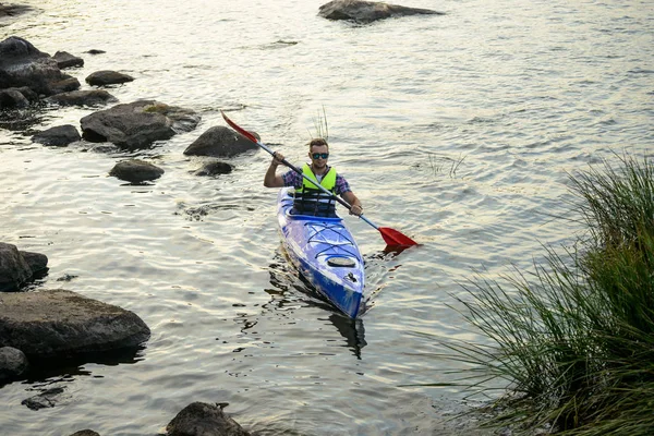 Homme pagayant kayak sur belle rivière ou lac parmi les pierres à la soirée — Photo