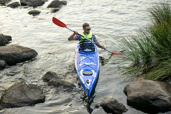 Homme pagayant kayak sur belle rivière ou lac parmi les pierres à la soirée — Photo