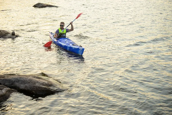 Man Paddling Kayak sul bellissimo fiume o lago tra le pietre alla sera — Foto Stock
