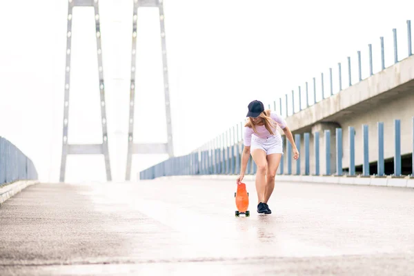 Young Beautiful Blonde Girl Riding Bright Skateboard on the Bridge — Stock Photo, Image