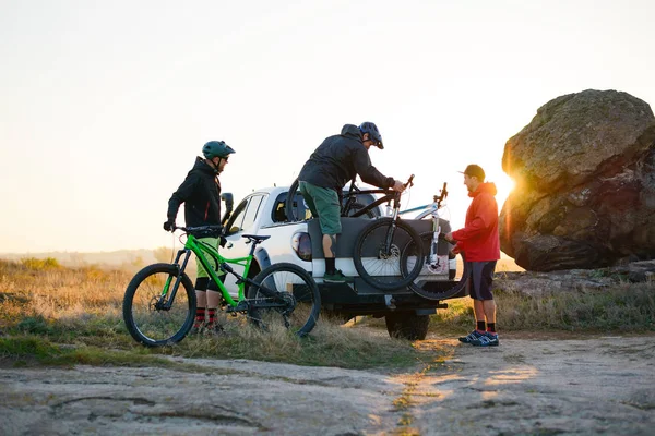 Amici Prendendo MTB Biciclette dal pick-up Offroad Truck in montagna al tramonto. Avventura e concetto di viaggio . — Foto Stock