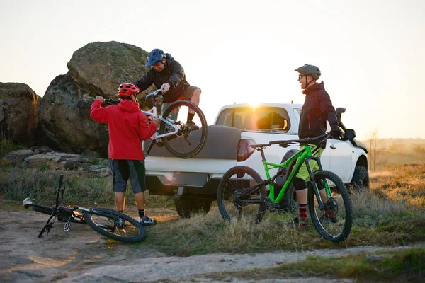 Amici Prendendo MTB Biciclette dal pick-up Offroad Truck in montagna al tramonto. Avventura e concetto di viaggio . — Foto Stock