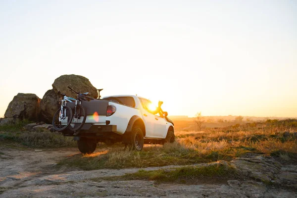 Amigos conduciendo camioneta todoterreno en las montañas con bicicletas en el cuerpo al atardecer. Concepto de aventura y viajes . — Foto de Stock