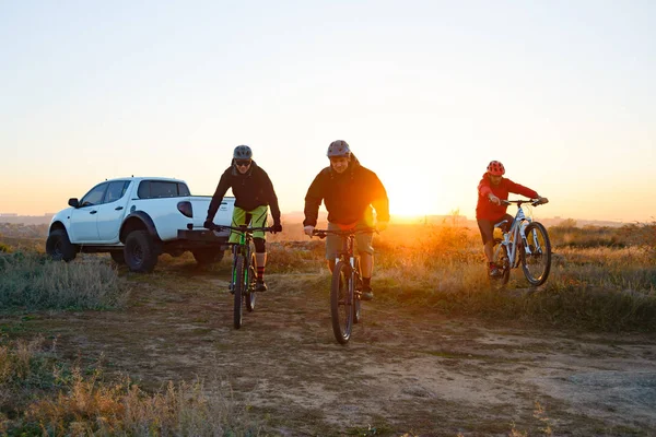 友人自転車エンデューロに乗ってバイク ピックアップ オフ道路トラック暖かい秋の夕暮れ時の目の前でマウンテン バイク冒険と旅行の車の概念 — ストック写真