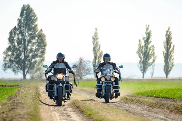 Due motociclisti che guidano moto da elicottero personalizzate su una strada sterrata d'autunno nel campo verde. Concetto avventura . — Foto Stock