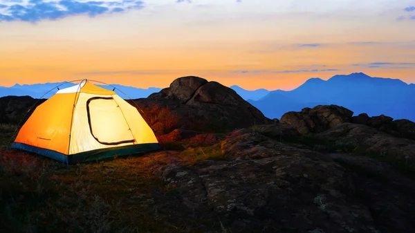 Gele verlichte Tent in de bergen van de avond Beautirul. Avontuur en reizen. — Stockfoto