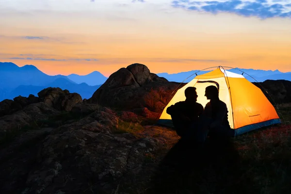 Çift oturma ışıklı çadır ve dağlarda Beautirul akşam birbirimize Looking — Stok fotoğraf
