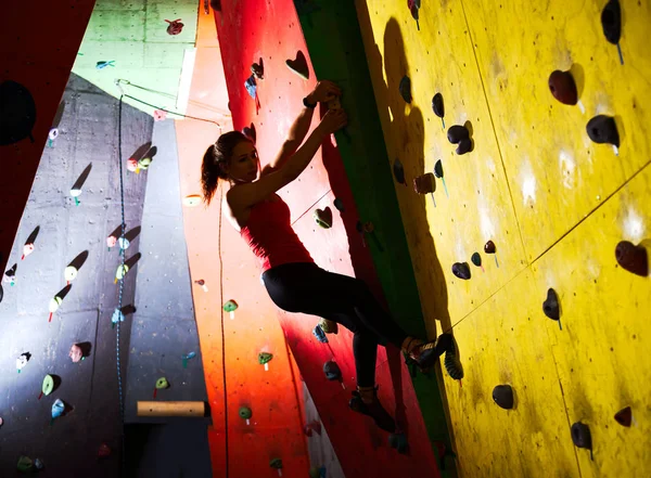 Joven Mujer Activa Bouldering on Colorful Artificial Rock in Climbing Gym. Deporte extremo y concepto de escalada interior —  Fotos de Stock